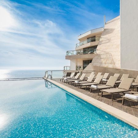 Sesimbra Hotel&Spa Exterior foto The photo showcases a luxurious infinity pool with crystal-clear water, reflecting the sky. Surrounding the pool are several sun loungers arranged neatly, inviting relaxation. In the background, there is a modern building with large glass balconies, 
